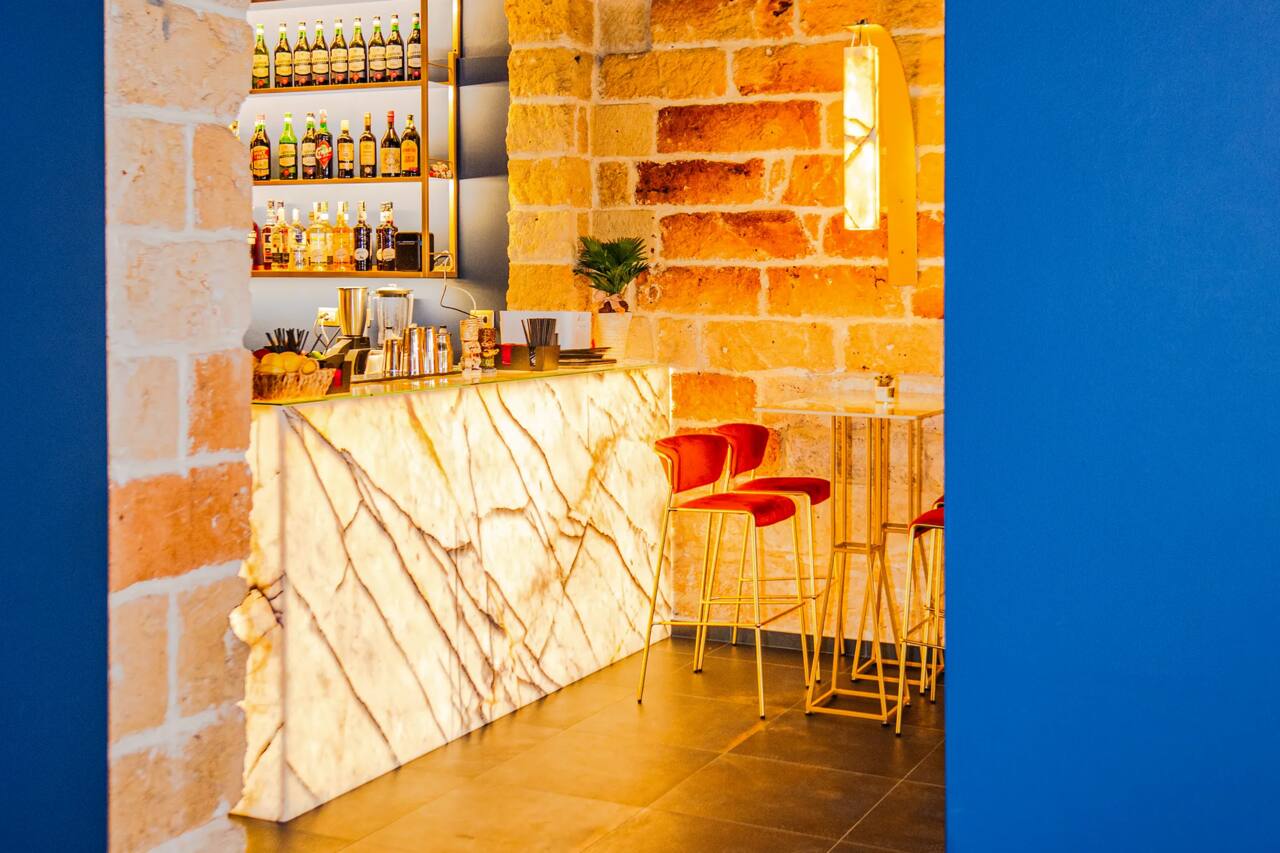 Il bancone in onice retroilluminato della zona drink, con la bottigliera e gli attrezzi da miscelazione